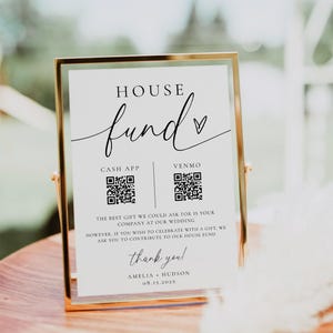 May include: A gold framed sign with the words "HOUSE fund" in elegant script. The sign includes QR codes for Cash App and Venmo, along with a thank you message and names. A wedding or event theme.