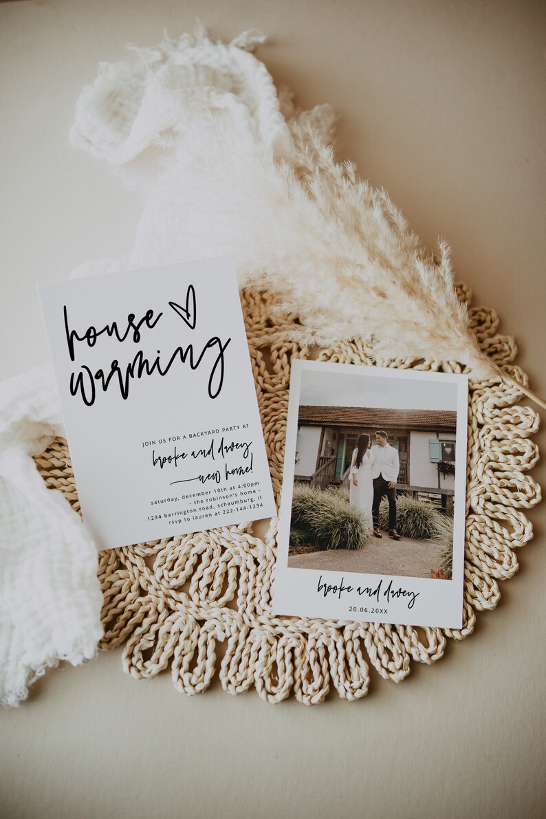 May include: A white card with black calligraphy that reads "house warming" and an invitation to a backyard party for Brooke and Dacey at their new home on December 10th at 4:00pm. The address is 1234 Barrington Road, Schaumburg, IL. RSVP to Lauren at 222-144-1234. A Polaroid photo of Brooke and Dacey standing in front of their new home is on the right side of the card.