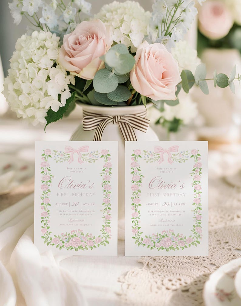 K&ouml;nnte beinhalten: Zwei Einladungskarten mit Blumen- und Schleifendesigns. Die Karten tragen die Aufschrift "Olivia's FIRST BIRTHDAY" mit dem Datum 20. August um 16:00 Uhr. Eine Vase mit einer gestreiften Schleife enth&auml;lt einen Strau&szlig; aus rosa Rosen, wei&szlig;en Hortensien und Gr&uuml;n.