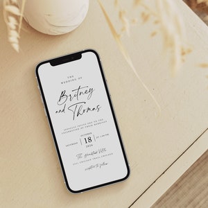 May include: A white smartphone displaying a wedding invitation for Britney and Thomas. The invitation states the wedding will take place on Saturday, October 18, 2022, at 5:00 PM at The Kinzie Hotel, 333 Chicago Trail, Chicago.
