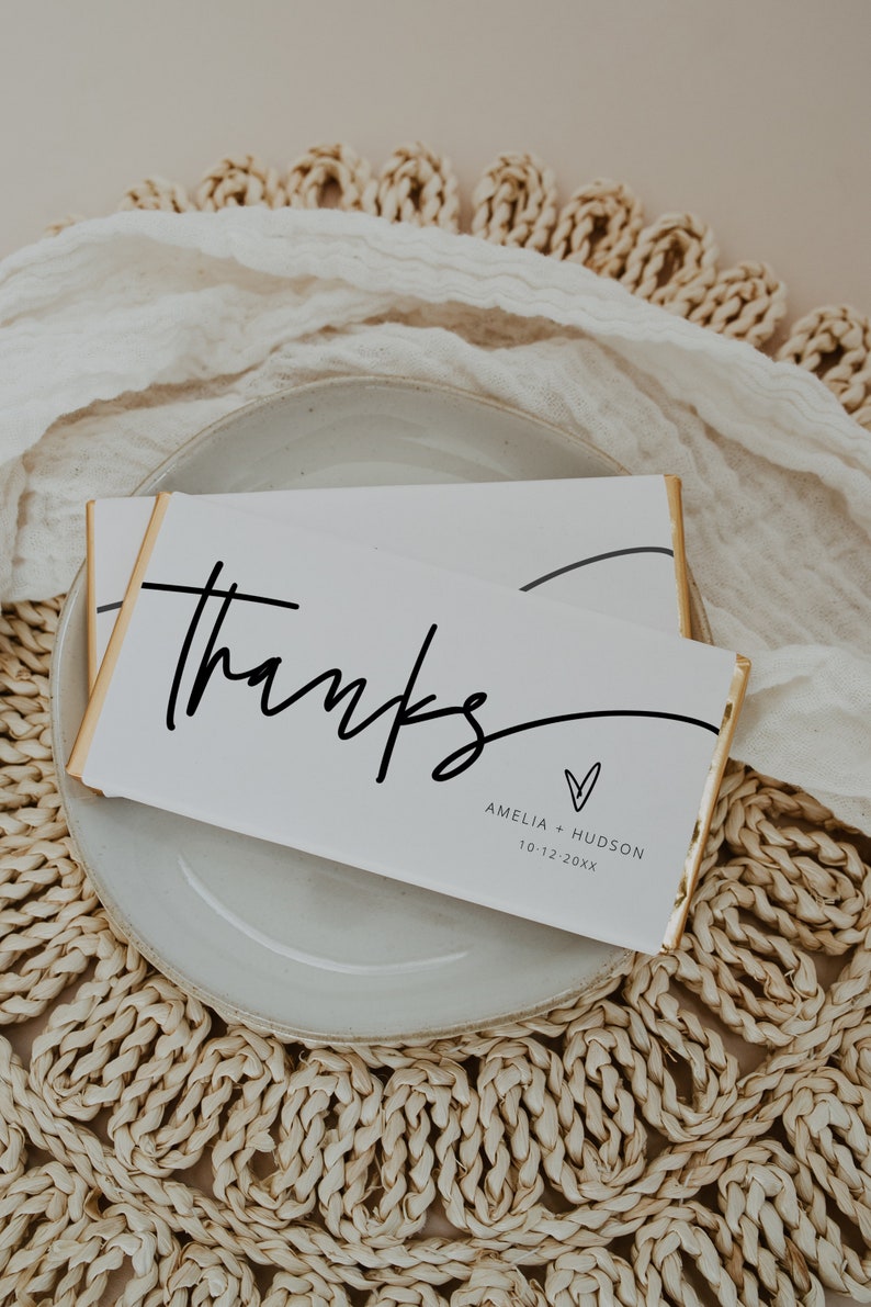 Peut inclure: Barre de chocolat blanc envelopp&eacute;e de papier d'or. La barre comporte un texte noir qui dit "merci" avec un c&oelig;ur et les noms Amelia + Hudson et la date 10-12-20XX.