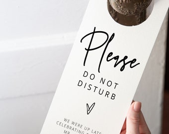 May include: White door hanger with black text that reads "Please Do Not Disturb" with a heart symbol and the text "We were up late celebrating the new Mr. and Mrs. Robinson".