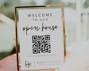 May include: A white sign with a gold frame, announcing an open house. The sign includes a QR code, the text "WELCOME TO OUR open house", and instructions to scan the QR code to sign in. The sign also includes a logo, social media icons, and a website address.