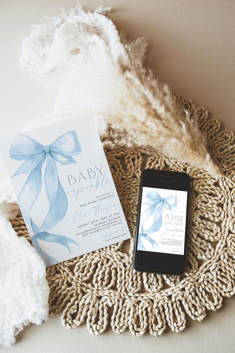 May include: A baby shower invitation and a smartphone displaying the same design. The invitation features a light blue watercolor bow and the words "BABY sprinkle". The phone is on a woven mat with decorative elements.