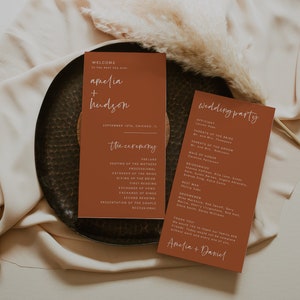 Może przedstawiać: Program ceremonii ślubnej z tłem w kolorze terakoty i białym tekstem. Program zawiera listę kolejności wydarzeń ceremonii, w tym preludium, usadowienie matek, procesję, wejście panny młodej, przekazanie panny młodej, pierwsze czytanie, wymianę przysięgi, wymianę obrączek, drugie czytanie, przedstawienie pary i wyjście. Program zawiera również listę gości weselnych, w tym urzędnika, rodziców panny młodej i pana młodego, druhny, druhen, świadka i świadków. Program kończy się podziękowaniem dla gości.