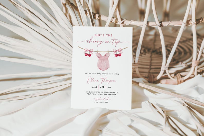 May include: A baby shower invitation with the text "She's the cherry on top" in a script font. The invitation features a pink onesie hanging on a clothesline with cherries and bows. The date and time of the shower are also included.