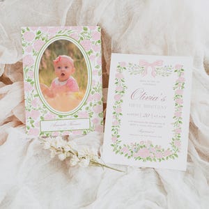 K&ouml;nnte beinhalten: Zwei Einladungskarten zum ersten Geburtstag eines Babys. Eine zeigt ein Foto in einem floralen Rahmen, die andere hat den Text "Olivias First Birthday" mit Datum und Uhrzeit. Beide sind mit rosa Blumen und einer rosa Schleife verziert.