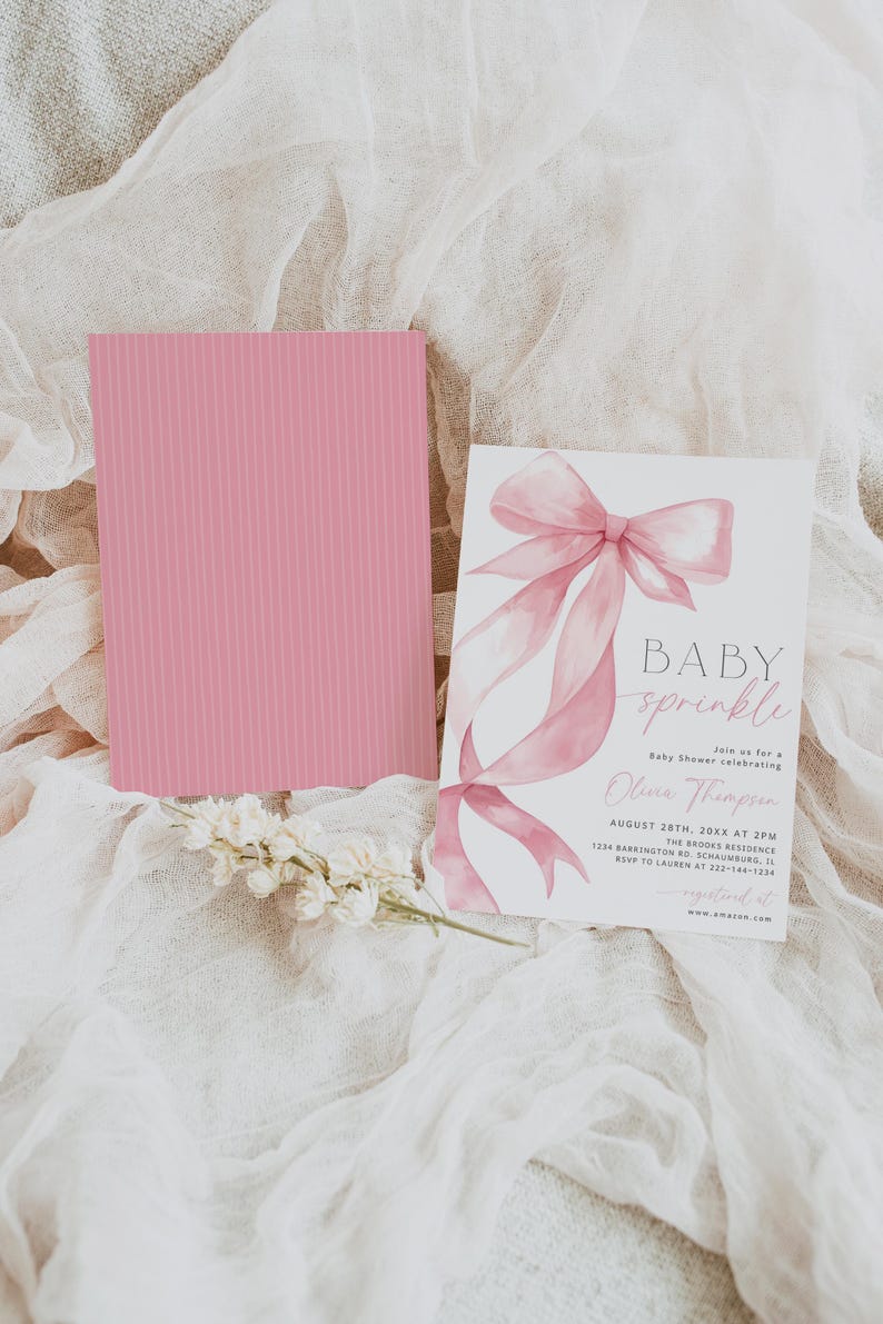 Pu&ograve; includere: Un invito per un baby shower con un design a fiocco rosa e le parole "BABY sprinkle". Una carta rosa con linee verticali &egrave; accanto all'invito. Fiori bianchi in basso.
