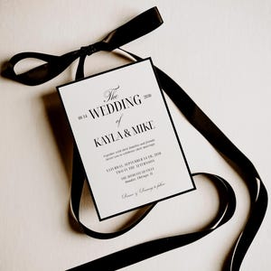 May include: A wedding invitation with black text on a white background, featuring the names Kayla & Mike. The invitation is accented with a black border and tied with a black satin ribbon. The text includes the date, time, and location.