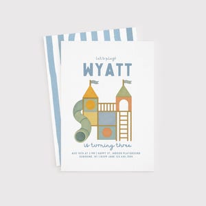 May include: A white invitation card with a blue striped backing. The front features a colourful playground illustration with the name "WYATT" and the text "is turning three". Includes event details.