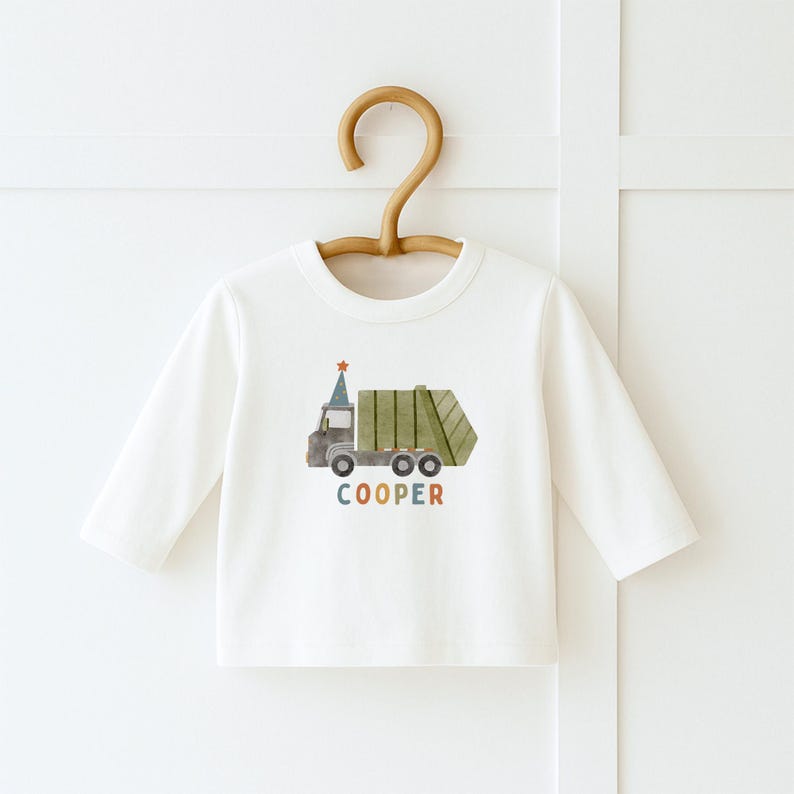 May include: White long-sleeve shirt with a green garbage truck graphic and the name "COOPER" in colorful letters.