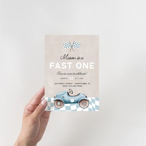 Op de afbeelding: Een blauwe en witte racewagen-thema verjaardagsuitnodiging met de tekst "Mason is a FAST ONE" en "Race on over to celebrate!"  12 augustus om 16:00 uur. 123 Happy Street - Happytown, FL. RSVP 123.456.7890.