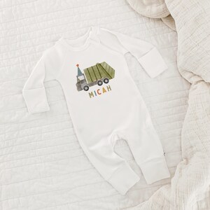 May include: White long-sleeve baby onesie with a green garbage truck and the name Micah printed on the front.