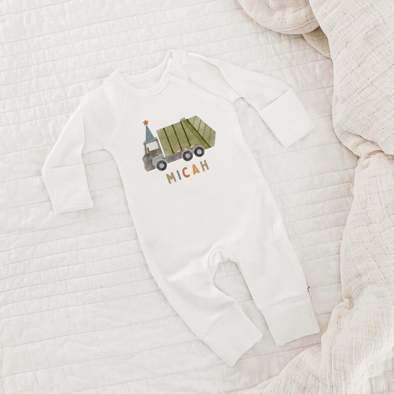 May include: White long-sleeve baby onesie with a green garbage truck and the name Micah printed on the front.