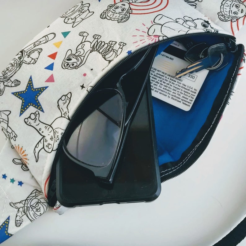 Puede incluir: Una bolsa blanca con cremallera con un estampado de dibujos animados de un perro, estrellas y fuegos artificiales. La bolsa est&aacute; abierta y contiene unas gafas de sol negras, un tel&eacute;fono inteligente negro y una tarjeta de cr&eacute;dito. La tarjeta de cr&eacute;dito tiene el texto "OURE NOT VALID UNLESS SIGNED FDIC, pursuant to a license from Visa U.S.A. Inc.  A 35 &euro; fee will be charged to replace your card after the valid thru date on the front of the card. For activation and PIN, please call and you consent to the cardholder agreement and serviced by Blackhawk Network."