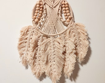 May include: A beige macrame dream catcher with wooden beads and fringe.