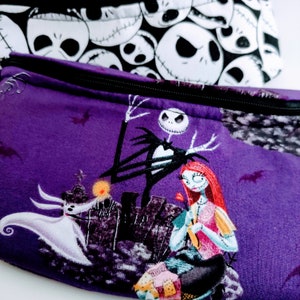 Może przedstawiać: Fioletowa kosmetyczka z zamkiem błyskawicznym z czarno-białym nadrukiem z filmu Koszmar przed świętami z przodu. Nadruk przedstawia Jacka Skellingtona i Sally.