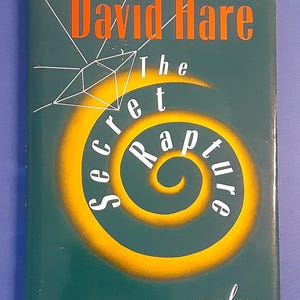 May include: A green book cover with the title "The Secret Rapture" by David Hare. The title is in white text with a yellow spiral design. The book is a play.