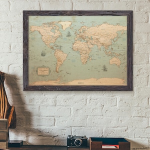 Puede incluir: Un mapa del mundo enmarcado con una est&eacute;tica vintage y desgastada. El mapa presenta una paleta de colores apagados con masas terrestres de color beige y un oc&eacute;ano azul claro. El marco marr&oacute;n oscuro complementa la apariencia envejecida del mapa. El mapa est&aacute; colgado en una pared de ladrillos blancos.