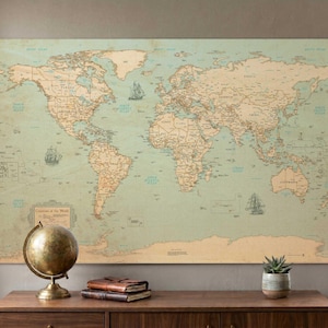 May include: A large world map print with a vintage aesthetic, featuring continents in tan and oceans in a muted teal. Decorative ships are scattered across the map. A brass globe and a succulent plant sit on a wooden surface below the map.