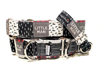 May include: A black, white, and red dog collar with a silver buckle. The collar has a patchwork design with a pattern of trees, mountains, and plaid. The collar has the text "Little Man" on it.
