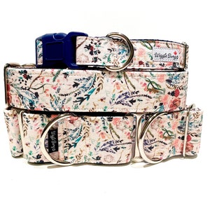 May include: Three dog collars in a floral pattern with a white background. The collars are stacked on top of each other. The top collar is a standard collar with a blue buckle. The middle and bottom collars are martingale collars with silver D-rings. The collars have a floral pattern with pink, blue, and green flowers. The collars have the text "Wiggle Buns" on the top collar.