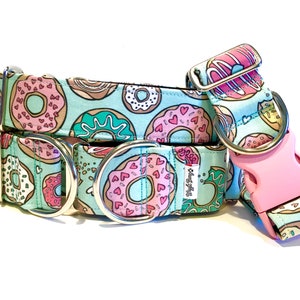 Könnte beinhalten: Ein türkisblaues Hundehalsband mit einem Donut-Muster. Das Halsband hat zwei silberne D-Ringe und eine rosafarbene Kunststoffschnalle. Das Halsband ist aus Stoff und hat ein weißes Etikett mit der Aufschrift "Collar & Cuffs".