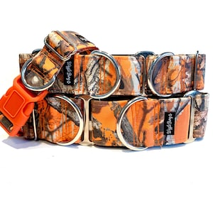 Op de afbeelding: Oranje en camouflage hondenhalsband met zilveren D-ringen en een feloranje plastic gesp. De halsband heeft de tekst "Wagging Dog Co." erop gedrukt.