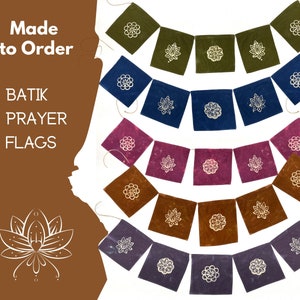 May include: A set of colourful batik prayer flags featuring a white lotus flower design. The flags are made to order and are ideal for adding a touch of spirituality to your home or garden.