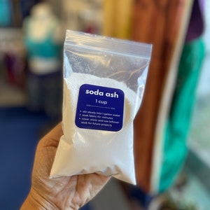 Peut inclure: Un sac en plastique transparent contenant une poudre blanche &eacute;tiquet&eacute;e "soda ash 1 cup". L'&eacute;tiquette comprend &eacute;galement des instructions pour utiliser la soude pour faire tremper le tissu : "m&eacute;langer lentement dans 1 gallon d'eau, faire tremper le tissu pendant 10 minutes, couvrir, conserver et utiliser le reste pour de futurs projets."