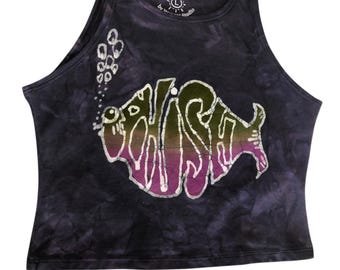 May include: A dark purple tie-dye tank top featuring a large graphic of a fish with the text "FISH" inside its body. The fish is colored with a gradient of green, yellow, and purple. A trail of bubbles rises from the fish. The neck label reads "hand dyed".