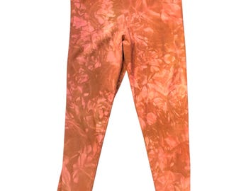 May include: A pair of leggings with a tie-dye pattern in shades of orange and pink. The leggings are made of a soft, stretchy material and have a comfortable waistband. The tie-dye design creates a unique and stylish look.