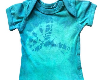 May include: A turquoise baby bodysuit with a tie-dye effect. The short-sleeved onesie features a faded blue design on the front. The garment has a round neckline and is made of soft fabric.