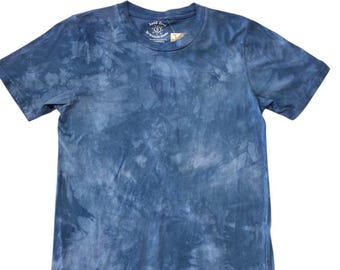 May include: A blue tie-dye t-shirt with a crew neck. The shirt has a tag on the collar with the text "hand dyed by Mason Shop". The shirt is made of a soft material and has short sleeves.