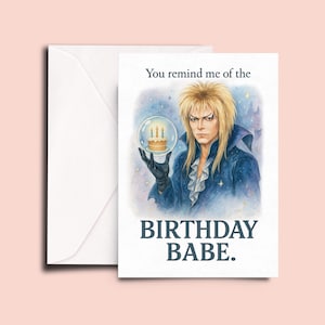 May include: A white greeting card with a watercolor illustration of a character holding a cake in a snow globe. The text reads "You remind me of the BIRTHDAY BABE."