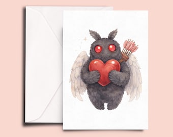 Könnte beinhalten: Eine Grußkarte mit einer Aquarellillustration eines dunkelgrauen, pelzigen Wesens mit roten Augen, das ein rotes Herz hält. Das Wesen hat kleine Flügel und einen Köcher mit Pfeilen. Links ist ein weißer Umschlag.