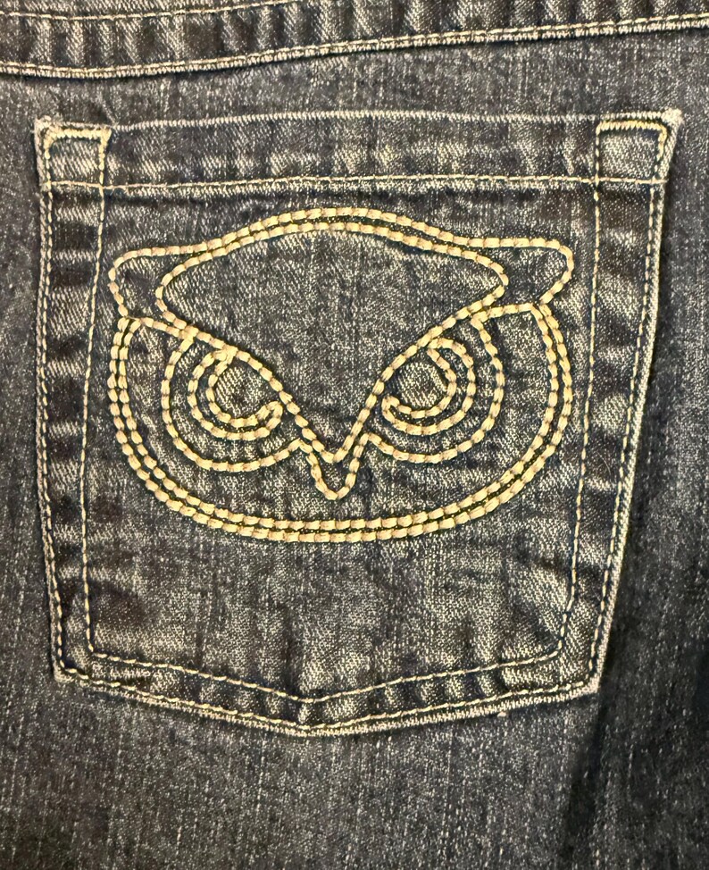 以下が含まれることがあります： 黒い持ち手と「But First, Coffee」のテキストが黒い太字で書かれた白いセラミックマグ。マグは白い表面に置かれています。マグの高さは約10cmです。