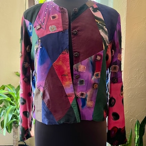 Może przedstawiać: Kurtka w stylu patchwork w wielu kolorach, z długimi rękawami i zapięciem na guziki. Kurtka jest wykonana z różnych materiałów i ma unikalny, artystyczny design.