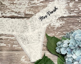 May include: White lace lingerie with the text "Mrs. Parish" embroidered on the waistband.