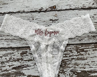 May include: White lace lingerie with the text "Mrs. Topham" embroidered in maroon.