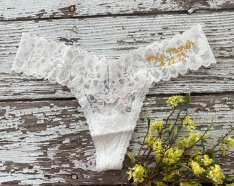May include: White lace lingerie with gold embroidery that reads "Mrs. Marsh 12.23".