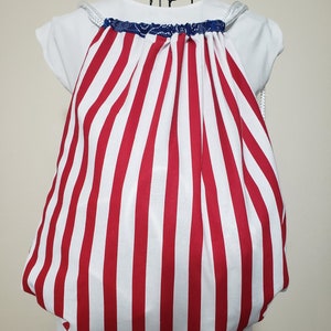 May include: Red and white striped drawstring bag with a blue and white trim. The bag is made of fabric and has a white drawstring.