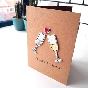 ¡Tarjeta de felicitación! Gafas de prosecco bordadas a movimiento libre hechas a mano y motivos de corazón montados en una tarjeta Kraft marrón A6 reciclada.