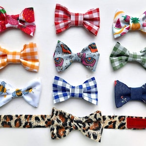 May include: Ten different bow ties with various patterns, including strawberries, gingham, bees, and watermelon. The bow ties are arranged in three rows on a white background.