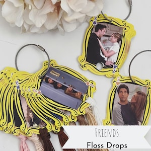 Könnte beinhalten: Ein Set gelber Bilderrahmen-Anhänger mit Bildern von Charakteren aus der Fernsehserie "Friends". Die Anhänger sind an einer silbernen Kette befestigt und haben bunte Quasten.