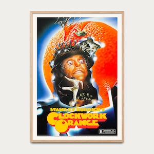 Könnte beinhalten: Gerahmtes Filmplakat für Stanley Kubricks "Uhrwerk Orange". Das Poster zeigt ein surreales Bild eines Mannes mit Metallkopfbedeckung, orange und blaue Farbtöne und den Filmtitel in Gelb und Rot.