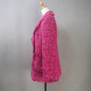 Side view of the custom hot pink bouclé blazer showing structured shoulders, fitted waist, and textured fringe details along the hem and sleeves.