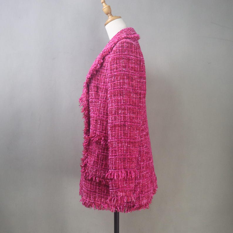 Side view of the custom hot pink bouclé blazer showing structured shoulders, fitted waist, and textured fringe details along the hem and sleeves.