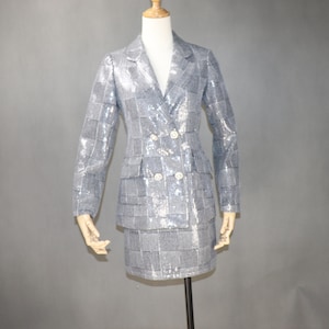 May include: A silver sequined blazer and skirt set with a double-breasted closure and a checkered pattern.