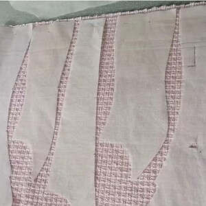 May include: A sewing project in progress, featuring fabric and pattern pieces. The fabric is a textured pink, and the pattern pieces are white, cut in curved shapes. The scene suggests garment construction.